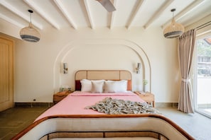 A bedroom with a wooden headboard, a pink bedspread, and a woven pendant light. - Staymaster White Castle-3BHK | Pvt Pool | Vagator  (Vagator)