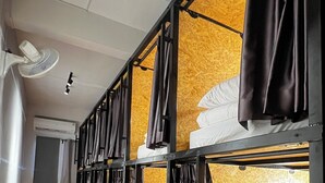 Ein Schlafraum im Schlafsaal-Stil mit Etagenbetten, Deckenventilator und Klimaanlage.