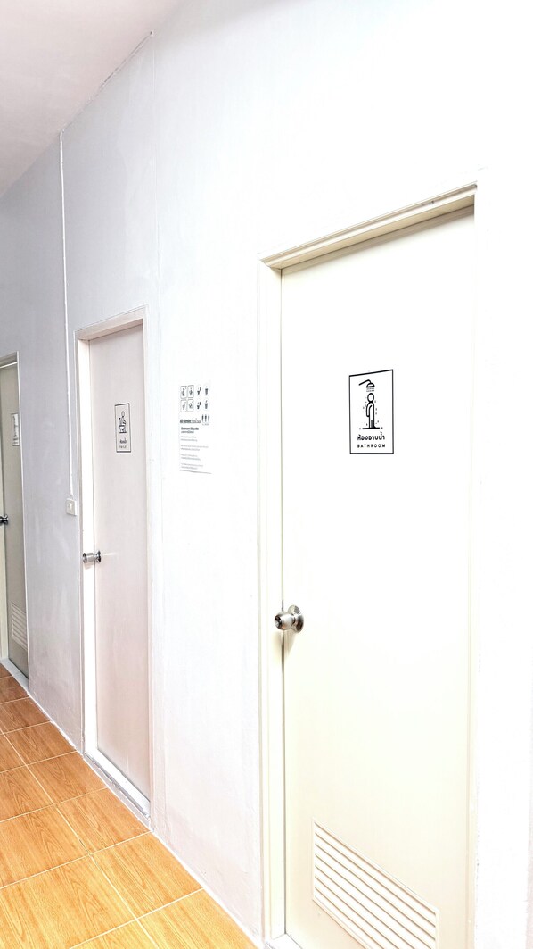 A hallway with white doors, one marked for a bathroom and another for a toilet. - Softbox Hostel (Rayong)