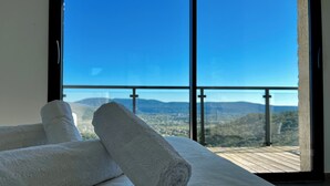 A room with a large window, a wooden floor, and two rolled white towels. - Exceptional villa with panoramic view and heated pool (Sampzon)