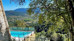 A stone wall, a pool, and a view of a valley with mountains. - Exceptional villa with panoramic view and heated pool (Sampzon)
