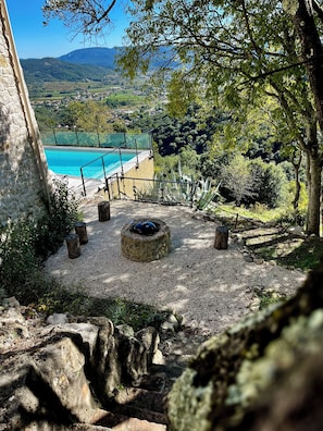 A stone wall, a pool, and a view of a valley with mountains. - Exceptional villa with panoramic view and heated pool (Sampzon)