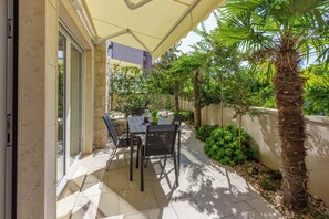Un patio al aire libre con una mesa, sillas, una palmera y piso de baldosas.