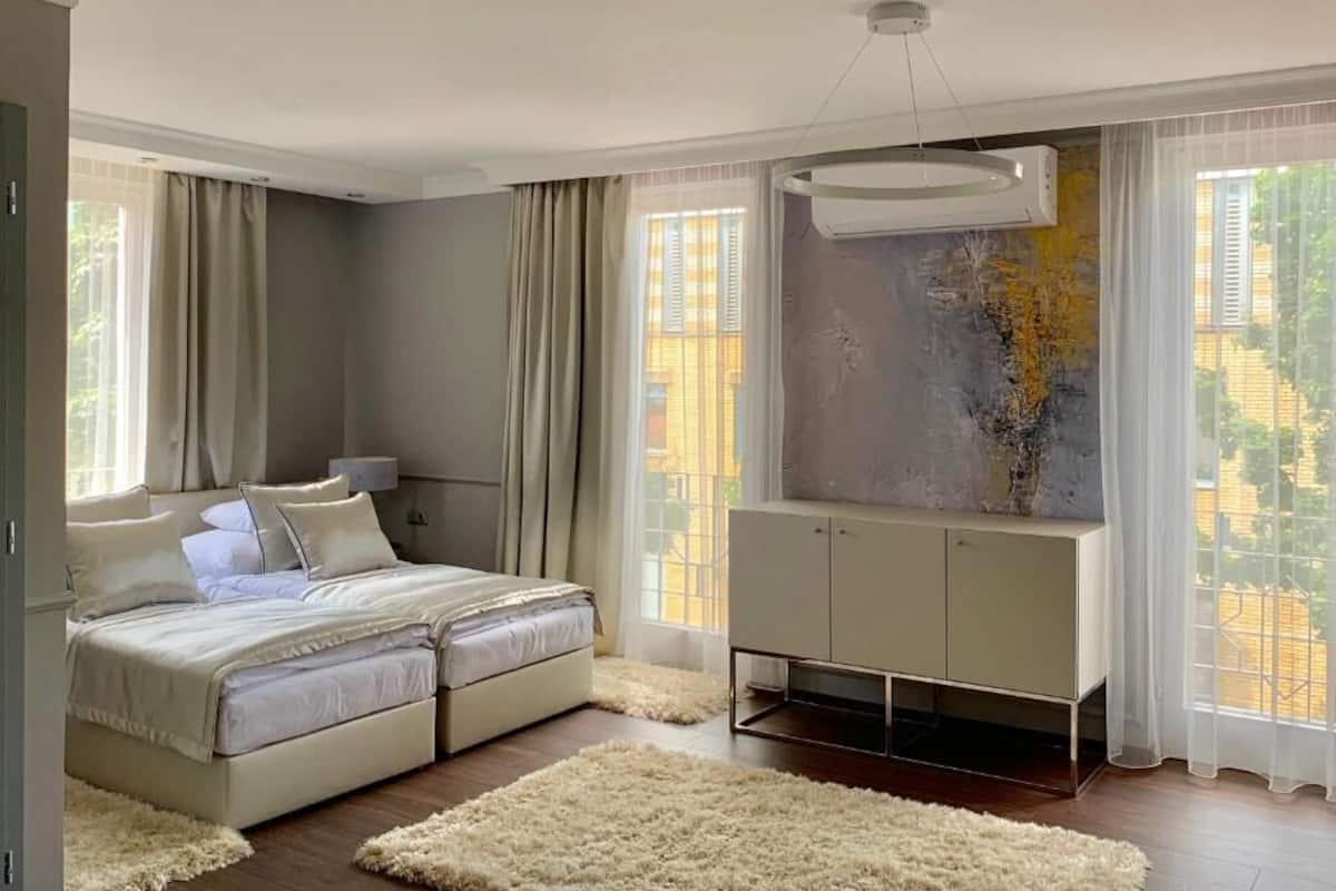 A modern bedroom with a bed, a white wardrobe, and a large window with curtains.
