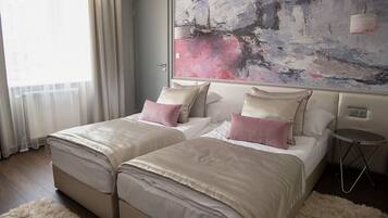 Habitación de hotel con dos camas, un cuadro abstracto grande en la pared, una mesita redonda pequeña y una alfombra mullida.