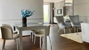 A modern living room with a dining area, featuring a glass table, contemporary chairs, and a decorative vase. - Boutique Hotel Center (Kecskemét)