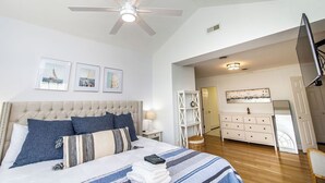 Ein Schlafzimmer mit Bett, Deckenventilator, Kommode und Fernseher.