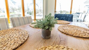Ein Holztisch mit gewobenen Tischsets, einem Blumentopf und Stühlen.