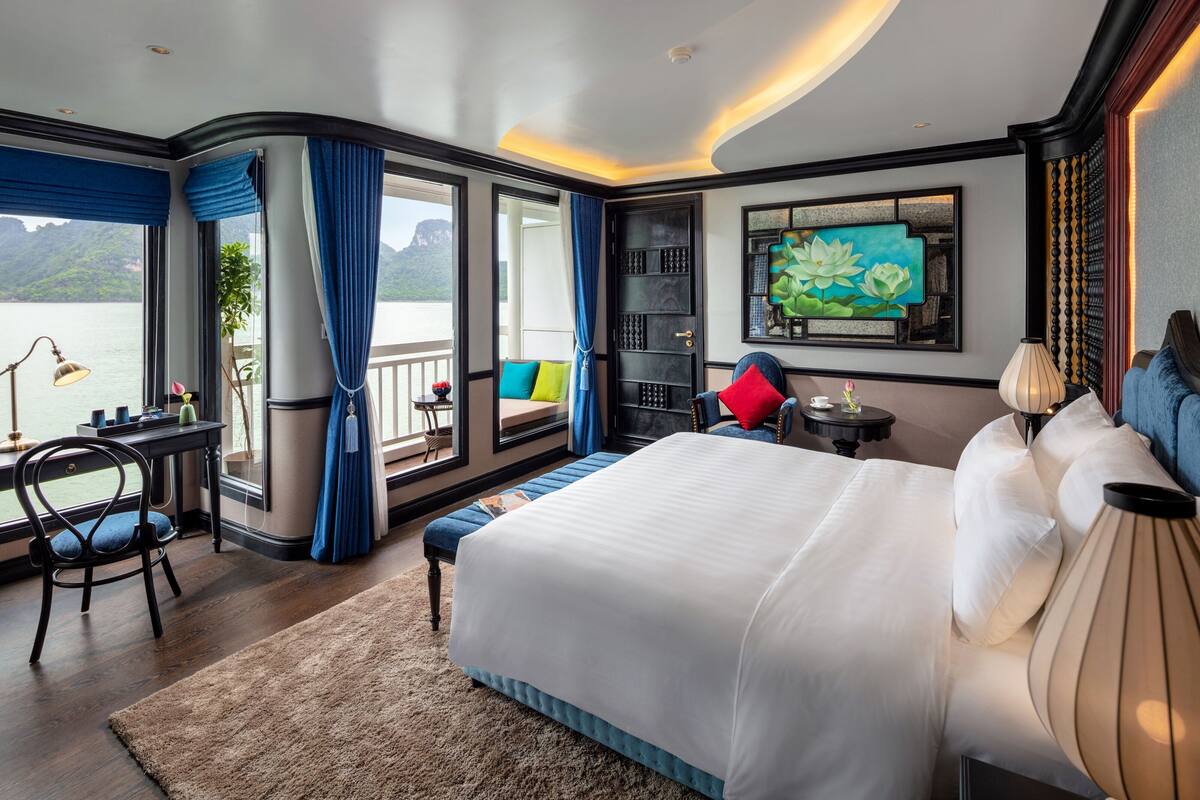 A bedroom with a large bed, a desk, and a view of a body of water.