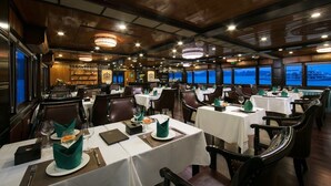 A restaurant with tables set for dining, featuring a view of the water outside.