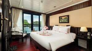 A hotel room with a bed, a chair, a nightstand, and a window with a view.