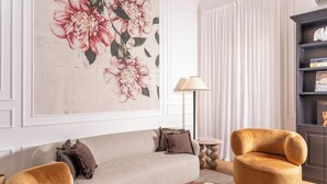 A living room with a beige sofa, two armchairs, a round coffee table, and a bookshelf. - N9 Tacito Design (Rome)