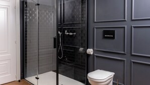 A modern bathroom with a glass-enclosed shower, a white toilet, and a dark tiled wall. - N9 Tacito Design (Rome)