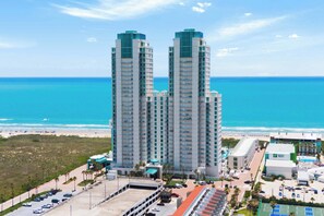 A high-rise hotel with multiple floors, a parking area, and a view of the beach and ocean. - Sapphire Beachfront - 17th Floor Views - Spa (South Padre Island)