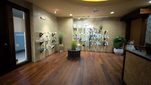 Een lobby met houten vloer, een receptiebalie en planken met diverse objecten.