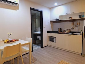 A compact kitchen with a dining area, featuring a microwave, stove, and various utensils. - Rawai Beach front The title Aparthotel by Perfect Rawai Holiday Homes (phuket)