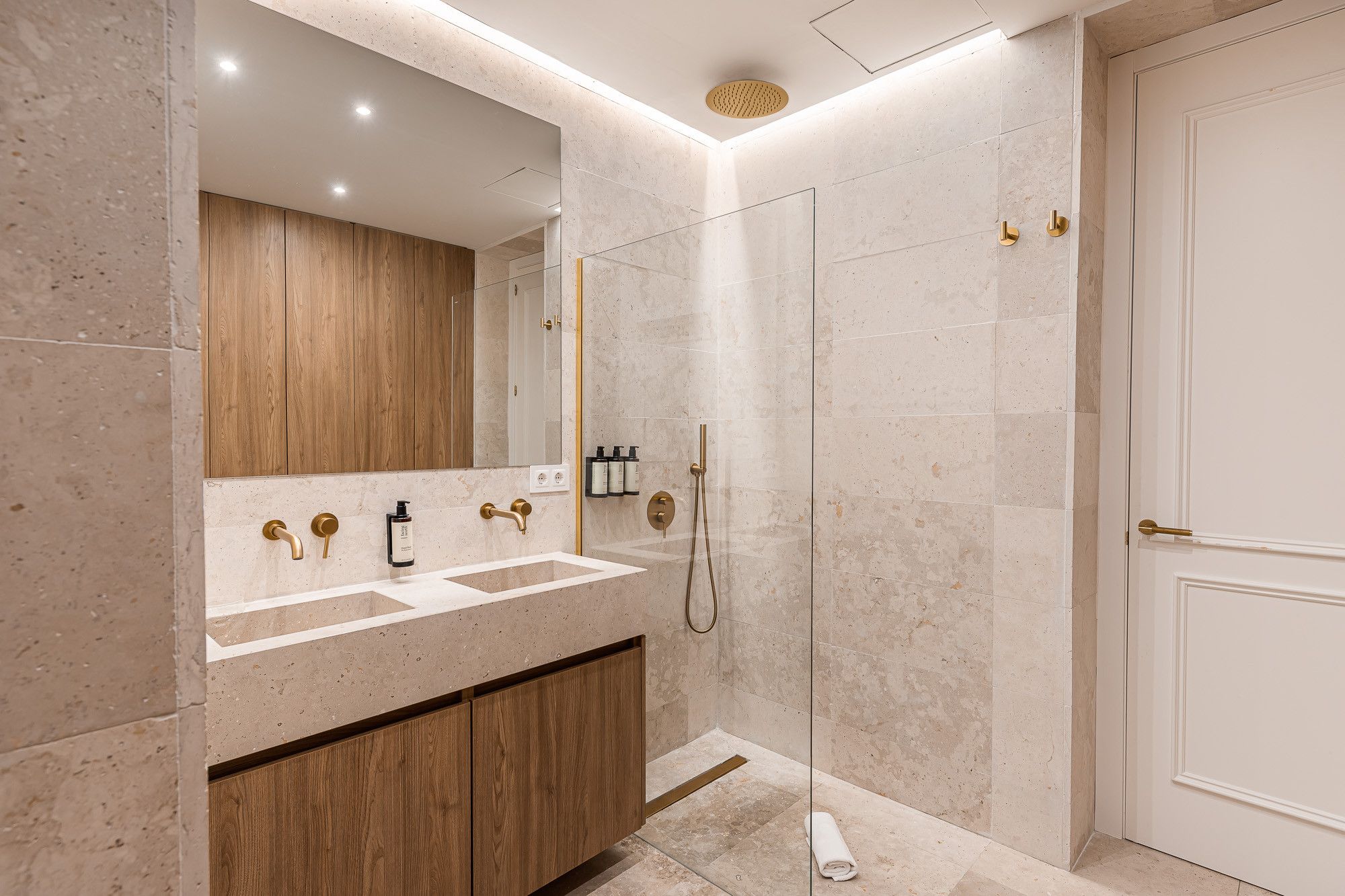 Un bagno moderno con un mobile lavabo doppio, una cabina doccia in vetro e un armadietto in legno.