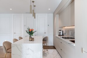 A modern kitchen with a marble island, pendant lights, and a coffee machine. - Waou Malasaña Luxe - Short-Term Rentals (Madrid)