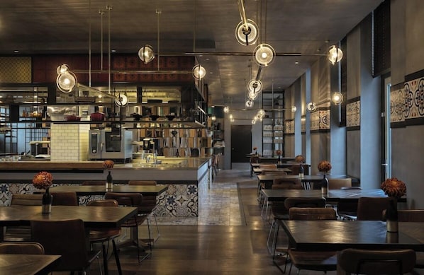 A restaurant with a bar area, dining tables, and hanging pendant lights. - Hotel Berlin Potsdamer Platz by Leonardo Hotels (Berlin)