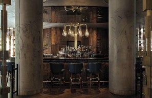A bar area with a wooden backdrop, a bar counter, and three bar stools. - Hotel Berlin Potsdamer Platz by Leonardo Hotels (Berlin)
