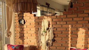 Un salon chaleureux avec un mur en briques, deux fauteuils confortables, une table basse en bois et un tapis tissé.