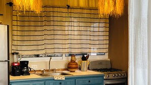 Une cuisine avec des armoires bleues, une cuisinière, un évier et deux luminaires suspendus.