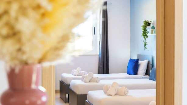 A hotel room with two beds, a window, and a potted plant. - Villa Delphi (Swieqi)