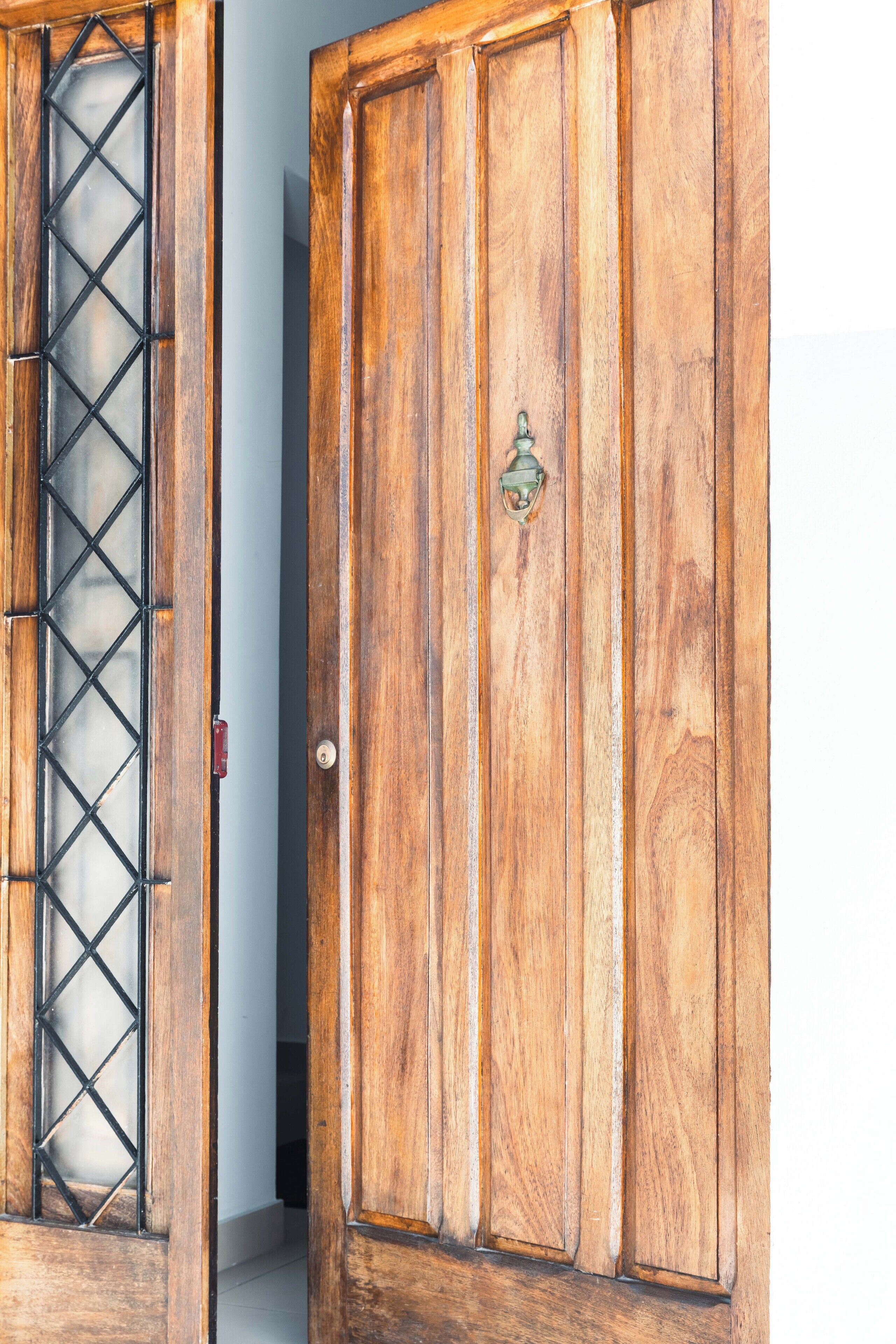 A wooden door with a metal grid window and a brass handle.