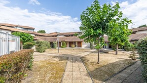 A courtyard with tiled roofs, a central tree, and a white fence.