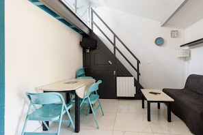 Um espaço compacto com área de refeições, sofá, escada e uma pequena mesa.
