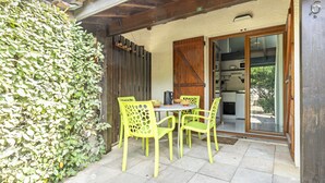 A patio with a table and chairs, a wooden door, and a view into a kitchen.