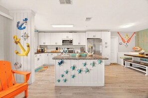 Een keuken met witte kasten, een centraal eiland en nautische decoraties.