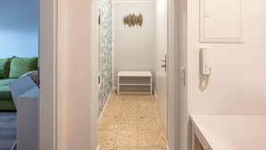 A narrow hallway with a bench, a door with a decorative panel, and a phone on the wall. - Vacation apartment Göttingen - modern apartments near the hospital & university (Göttingen)