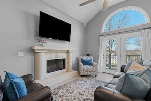 A living room with a fireplace, a television, a sofa, and a chair. - Pointe Royale Golf | Garage | King | Queen | Bunk (Branson)