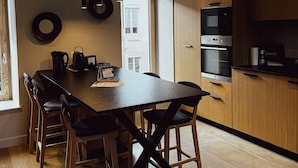 Een moderne keuken met een groot eiland, houten kasten en een eethoek met stoelen.