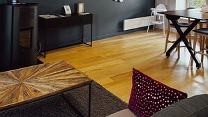 Een moderne woonkamer met een zwarte muur, een ronde spiegel, een open haard en een eethoek met een tafel en stoelen.
