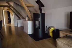 A modern living room with a wood-burning stove, a wooden staircase, and a cozy seating area.