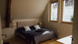 A bedroom with a bed, two bedside tables, a window, and a wooden floor.