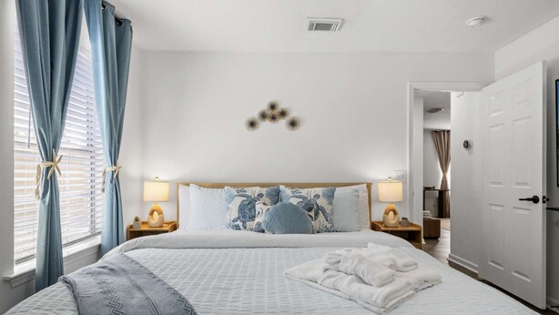 A bedroom with a bed, bedside lamps, a starfish decoration, and a door.