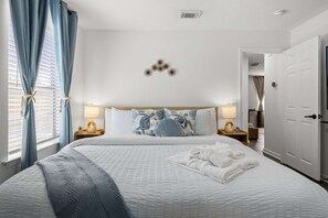 Un dormitorio con una cama, lámparas de noche, un adorno con forma de estrella de mar y una puerta.