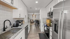 A modern kitchen with white cabinets, stainless steel appliances, and a granite countertop.