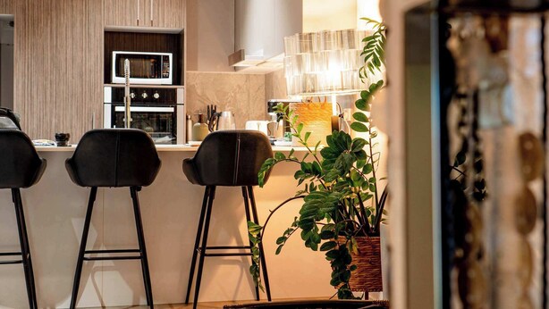 Eine moderne Küche mit Barhocker, Mikrowelle, Backofen und einem Blumentopf.