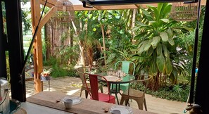 A covered outdoor dining area with a table and chairs, surrounded by lush greenery and a bamboo structure. - L'Oasis des Colibris – Tiny House & Spa in L'Étang-Salé (L'Étang-Salé)