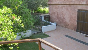 Un patio con un banco de madera, una maceta de piedra y un suelo de baldosas.