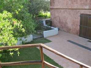 A courtyard with a wooden bench, a stone planter, and a tiled patio.