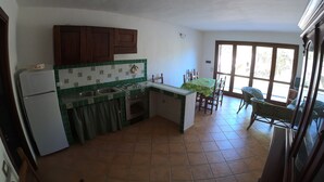 Una cocina compacta con refrigerador, pileta y estufa. Hay un comedor con mesa y sillas.