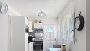 Eine kompakte Küche mit Mikrowelle, Backofen und einem Essbereich mit Tisch und Stühlen.
