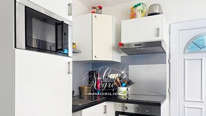 Eine kompakte Küche mit Mikrowelle, Backofen und Kaffeemaschine auf der Arbeitsfläche.