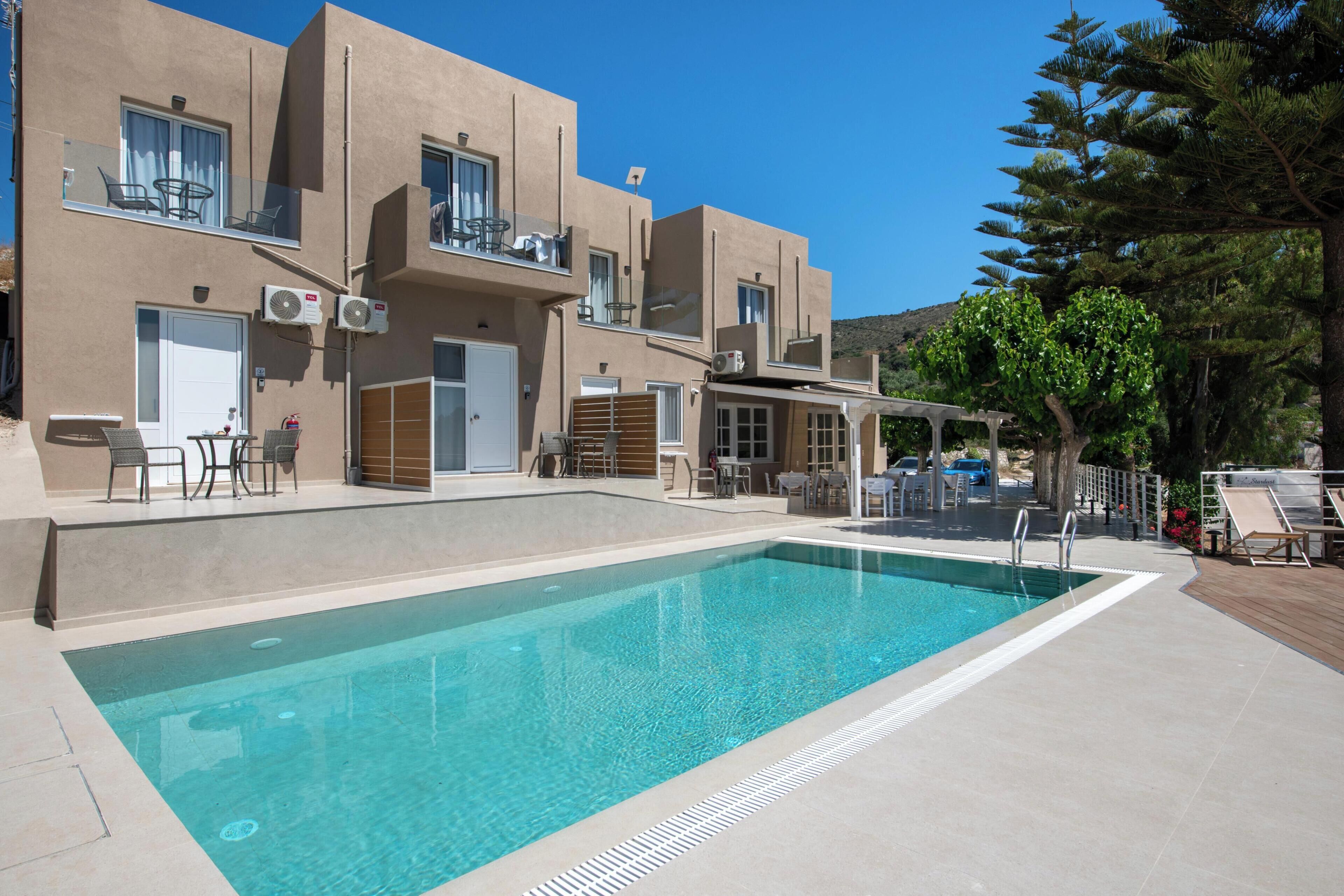 Una piscina al aire libre, sombrillas, sillones reclinables de piscina