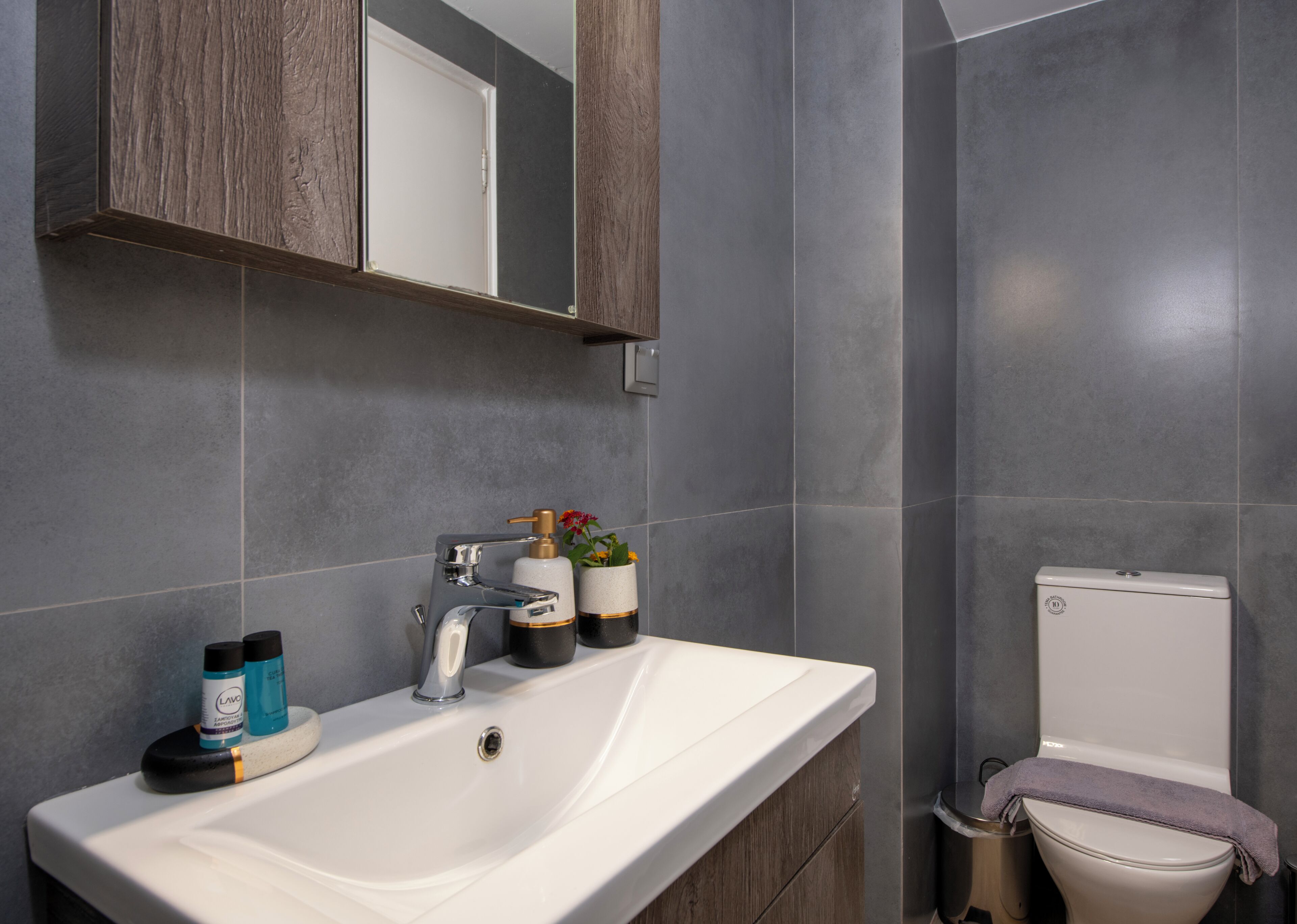 Un baño con lavamanos blanco, espejo, inodoro y zona de ducha.